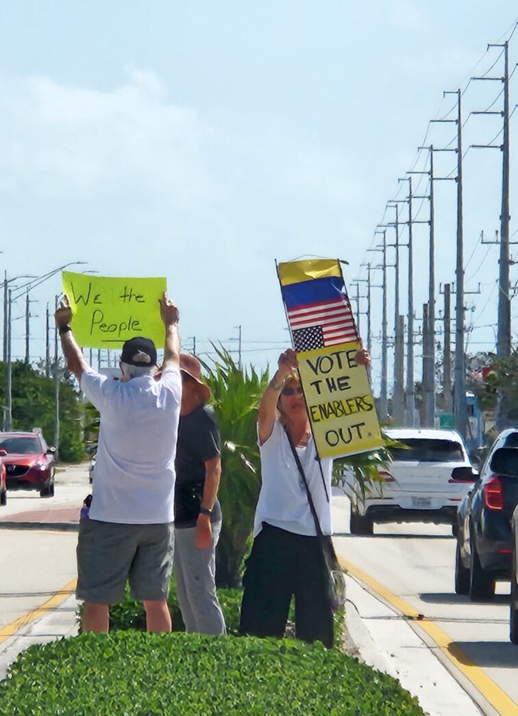 a group of people holding signs on the side of a road