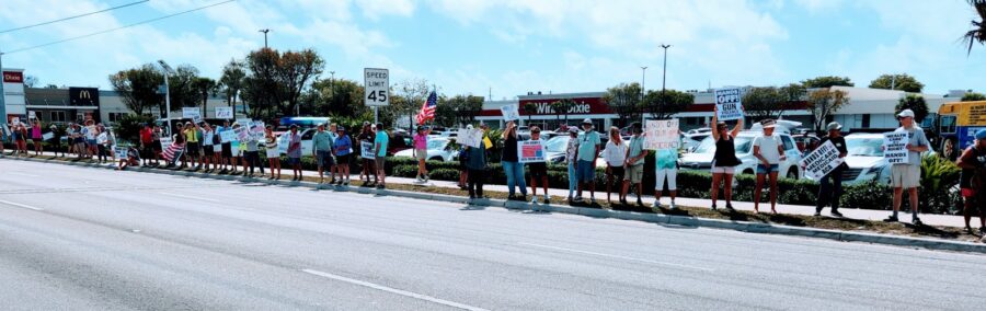 a long line of people holding signs on the side of a road