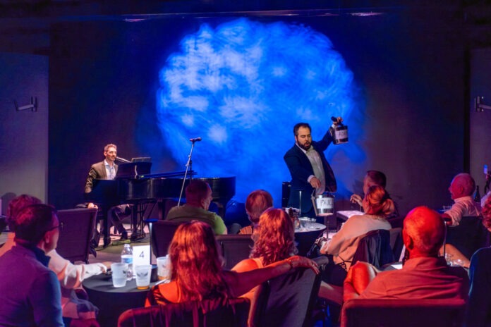 a group of people sitting at tables in front of a stage