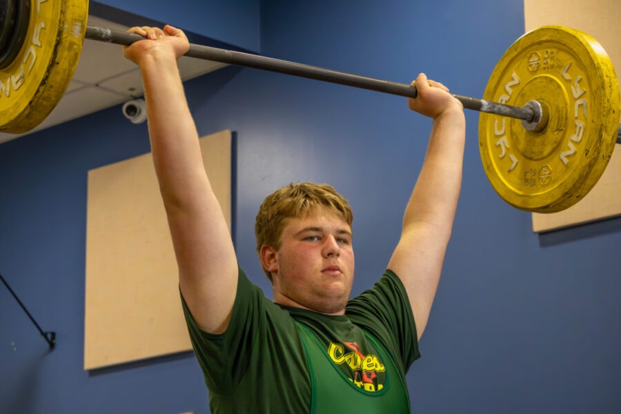 a young man lifting a barbell in a gym