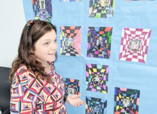 a woman standing in front of a quilt