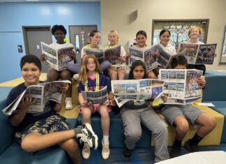 a group of people sitting on a couch reading newspapers