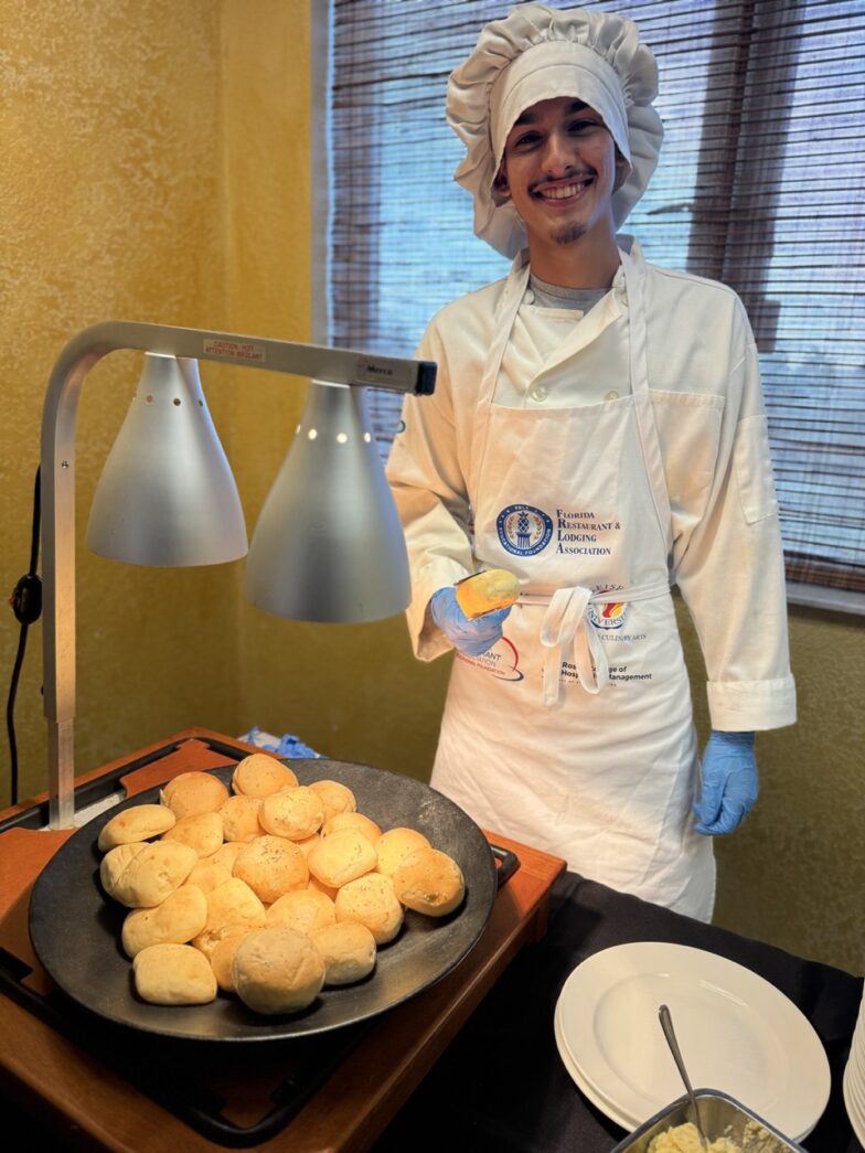 a woman in a chef's outfit standing next to a tray of food