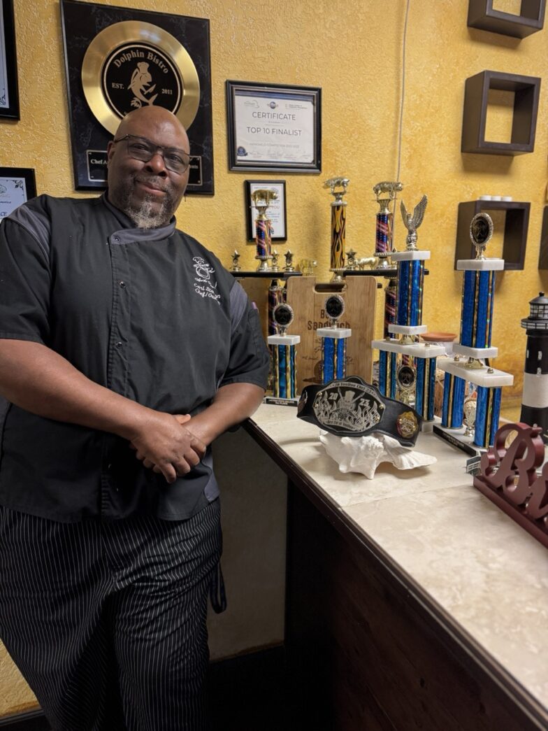 a man standing in front of a counter with trophies