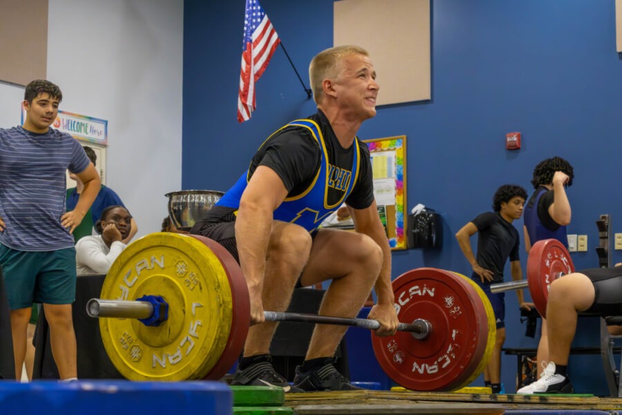 a man squatting on a bench with a barbell in front of him