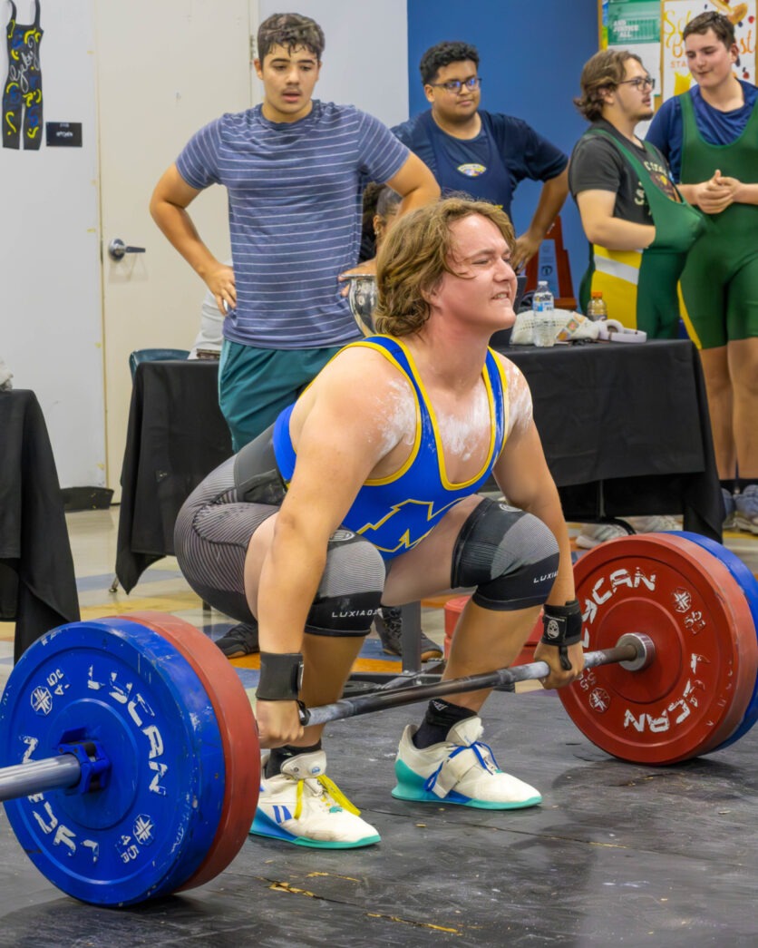a man squatting down while holding a barbell