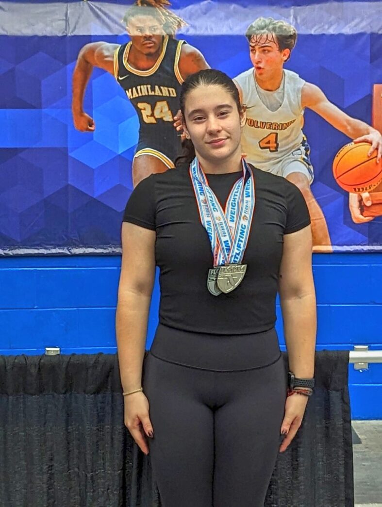 a woman standing on a basketball court holding a medal