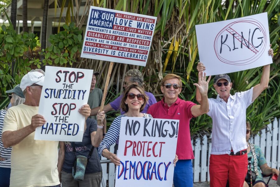 a group of people holding signs in front of a fence