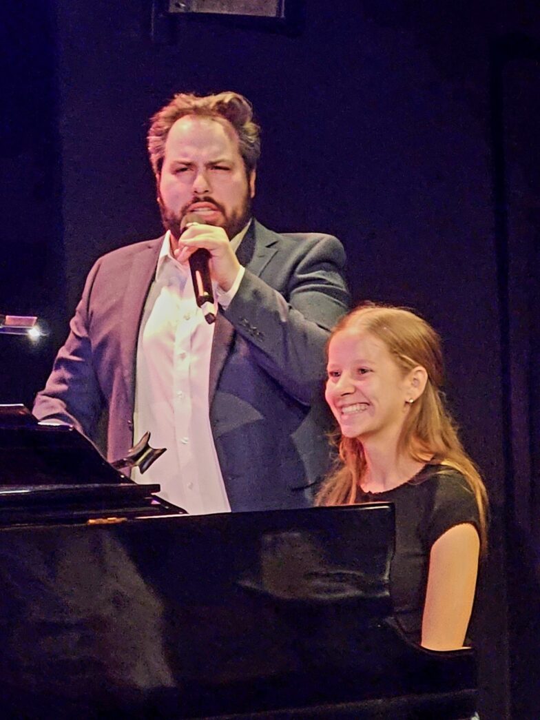 a man and a woman standing next to a piano