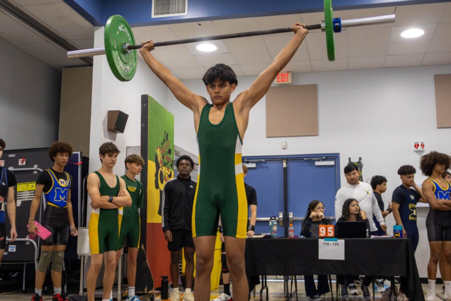 a man holding a barbell in front of a group of people