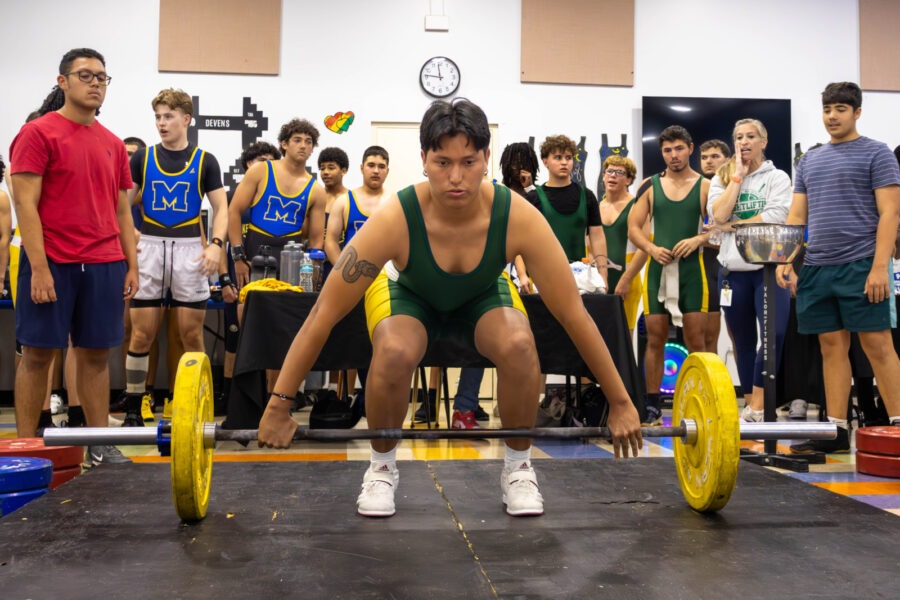 a man squats on a barbell in front of a group of people