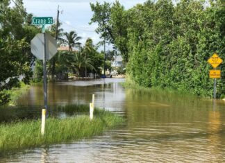 a flooded street with a street sign in the middle of it