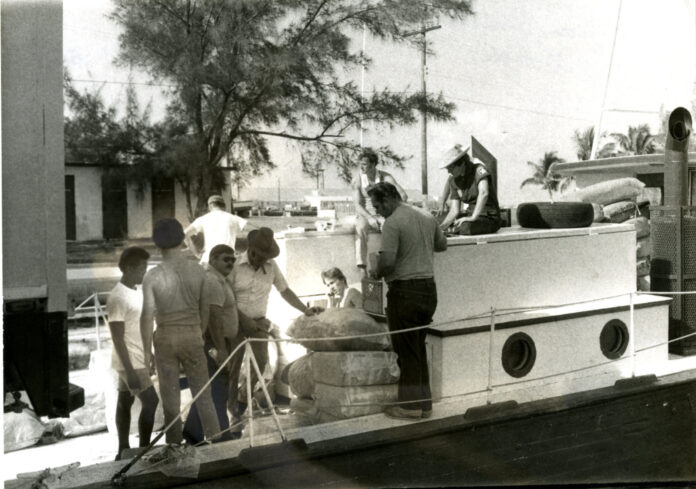 Unloading Bales Wright Langley Coll a black and white photo of a group of people on a boat