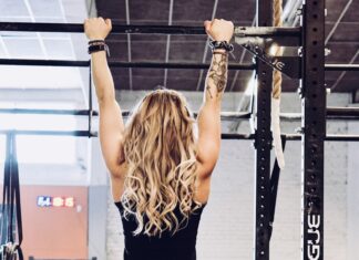 a woman in a black tank top is doing a pull up