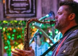 a man playing a saxophone in front of a christmas tree