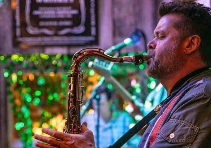 a man playing a saxophone in front of a christmas tree
