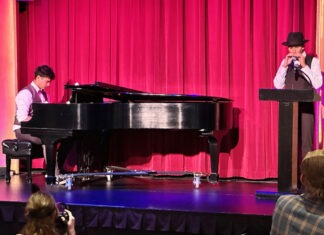 a man standing on a stage next to a piano