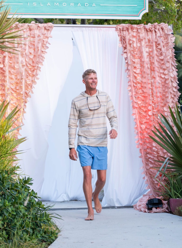 a man walking down a sidewalk under a sign