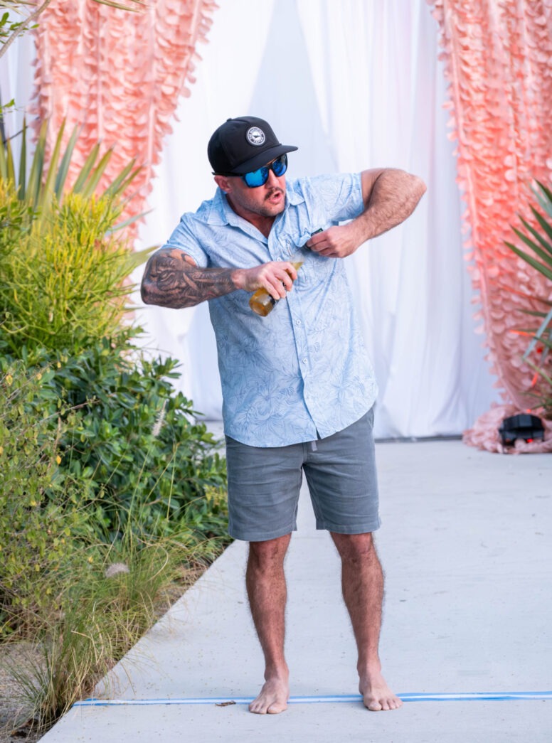 a man standing on a sidewalk holding a bottle of beer
