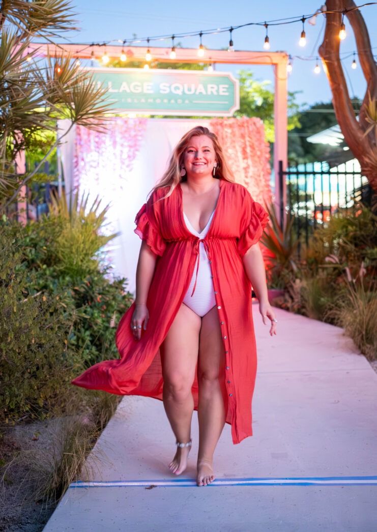 a woman walking down a sidewalk in a bikini