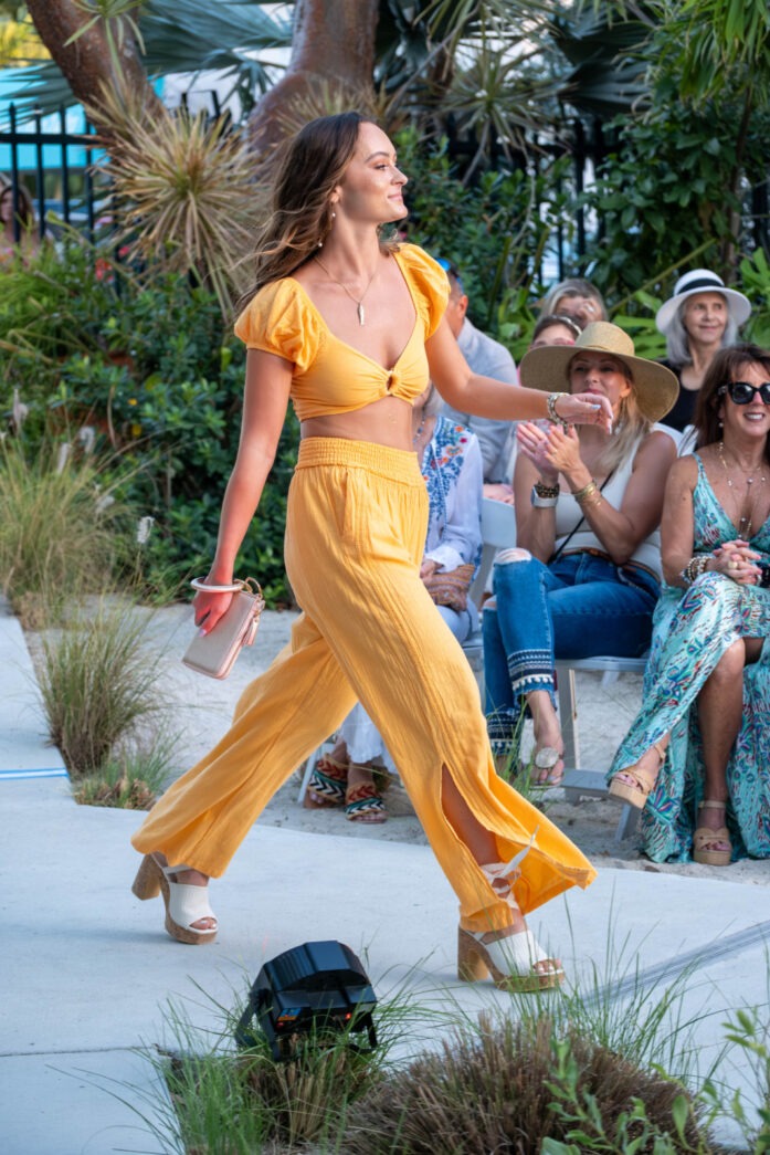 a woman in a yellow outfit is dancing on a sidewalk