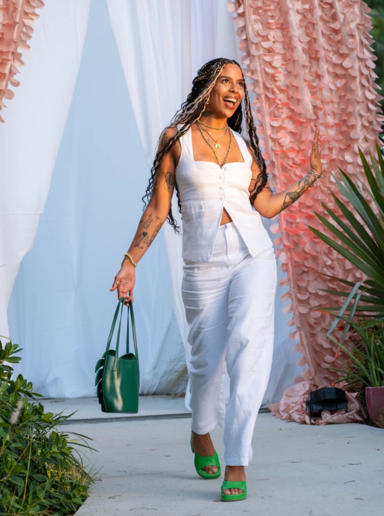 a woman walking down a runway carrying a green purse