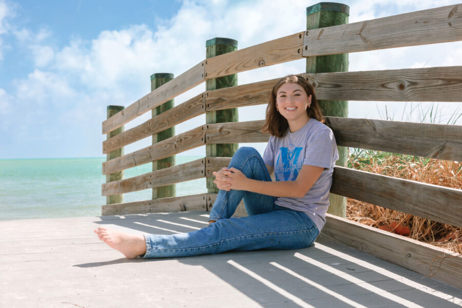 a woman sitting on a wooden bench next to the ocean