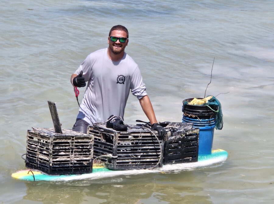 a man standing in the water with a boat made of crates