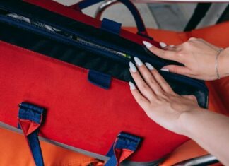 Close-up of a woman's hands opening a red medical bag, highlighting emergency preparedness.