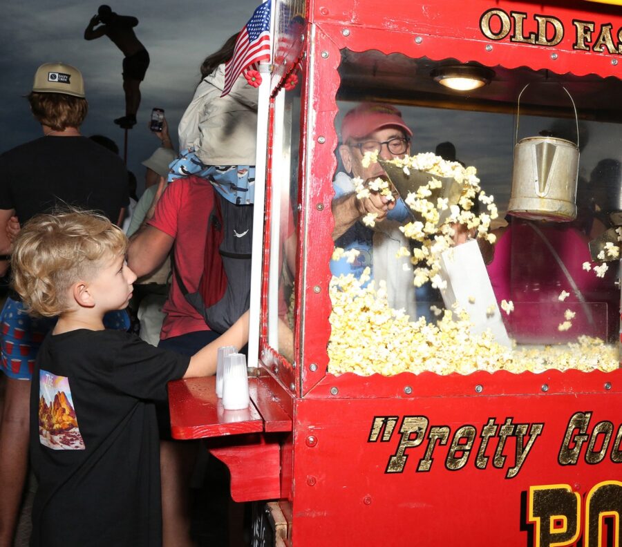 a little boy standing in front of a popcorn machine