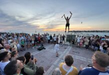 a crowd of people standing around a man on top of a pole