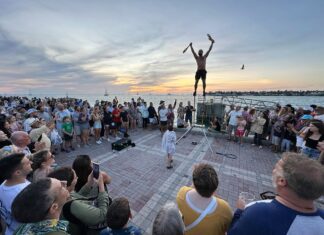 a crowd of people standing around a man on top of a pole