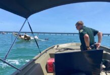 a man standing on the back of a boat in the ocean