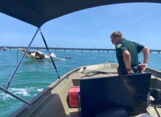 a man standing on the back of a boat in the ocean