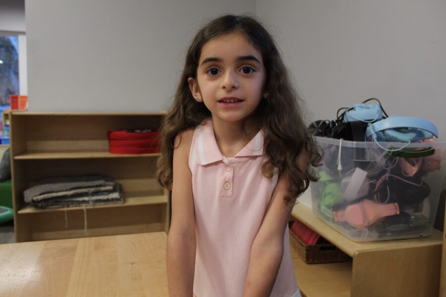 a girl in a pink dress standing in a room