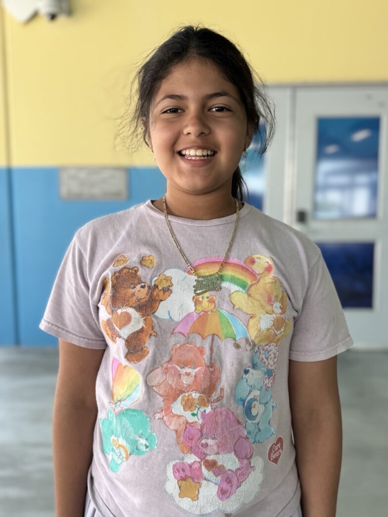 a girl standing in a room with a teddy bear t - shirt on