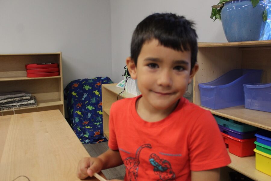 a young boy sitting at a table in a classroom