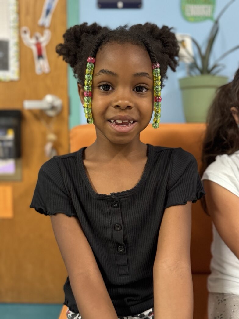 a young girl sitting on a chair in a classroom