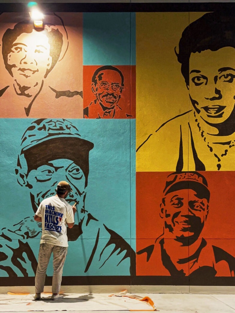 a man standing in front of a wall with a painting on it