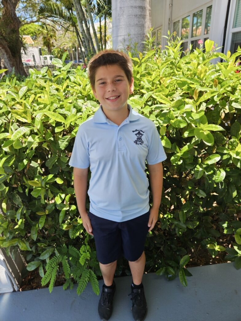 a young boy standing in front of a bush