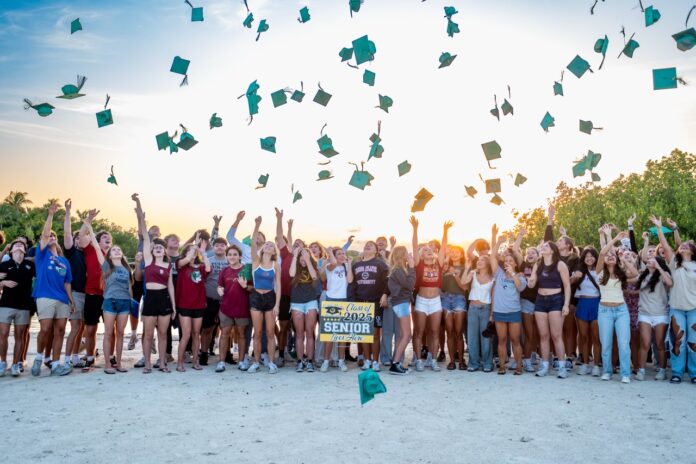 CS grads 8 Large a group of people standing on top of a sandy beach