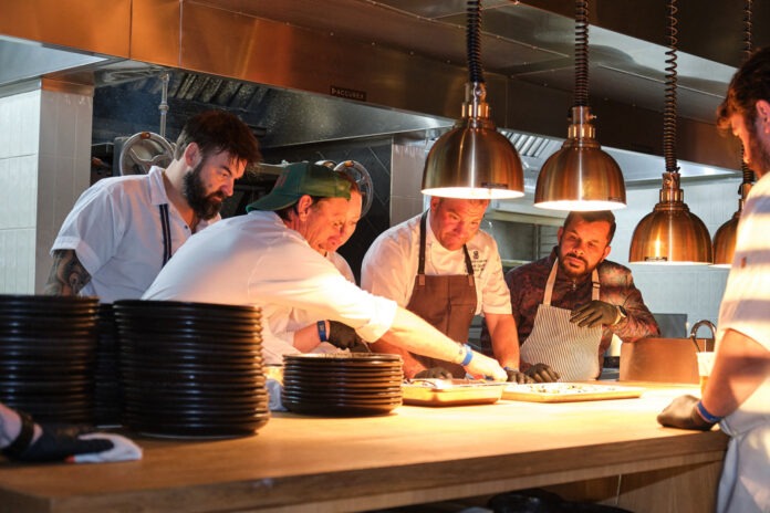 Chef Brandon McGlamery in action a group of men in a kitchen preparing food