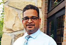 a man wearing glasses and a tie standing in front of a building