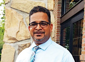 a man wearing glasses and a tie standing in front of a building