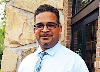 a man in a dress shirt and tie standing in front of a building