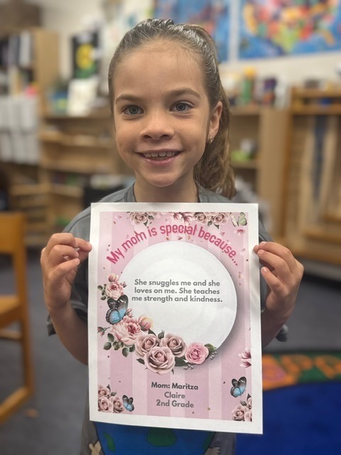 a young girl holding up a sign in a classroom