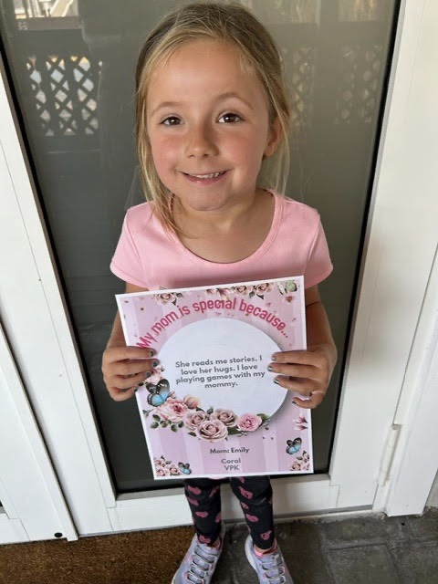 a little girl holding up a book with a picture on it
