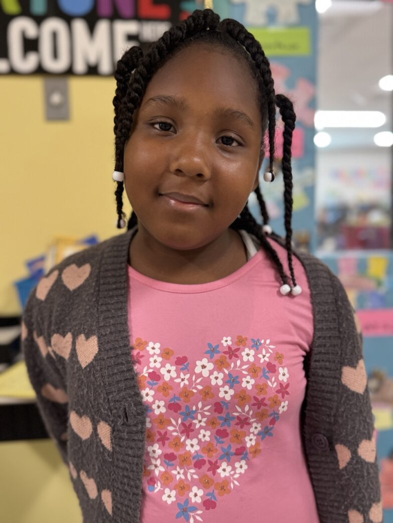 a young girl standing in front of a bulletin board