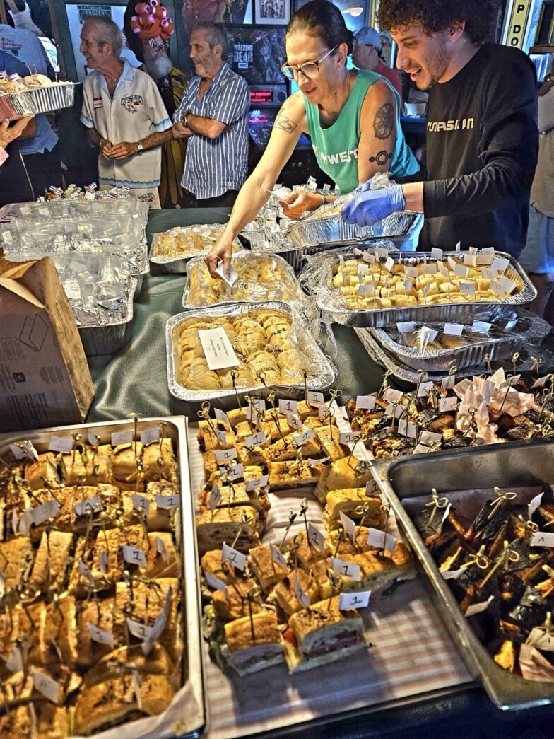 a group of people standing around a table filled with food