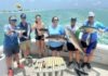 a group of people on a boat holding fish
